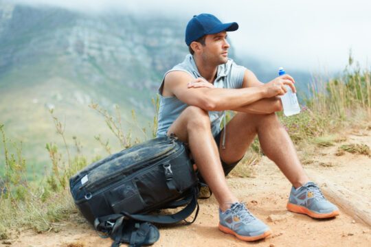 taking a well deserved break. young hiker sitting down and takin