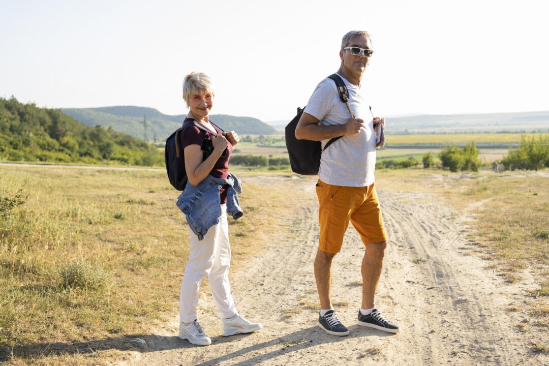 Couple senior marchant sur un chemin en pleine nature avec un sac à dos, symbolisant le rucking après 60 ansCouple senior marchant sur un chemin en pleine nature avec un sac à dos, symbolisant le rucking après 60 ans
