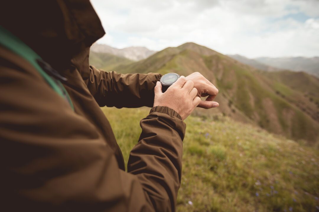 Ruckeur en haute montagne vérifiant l’altitude sur sa montre GPS pendant une marche sportive