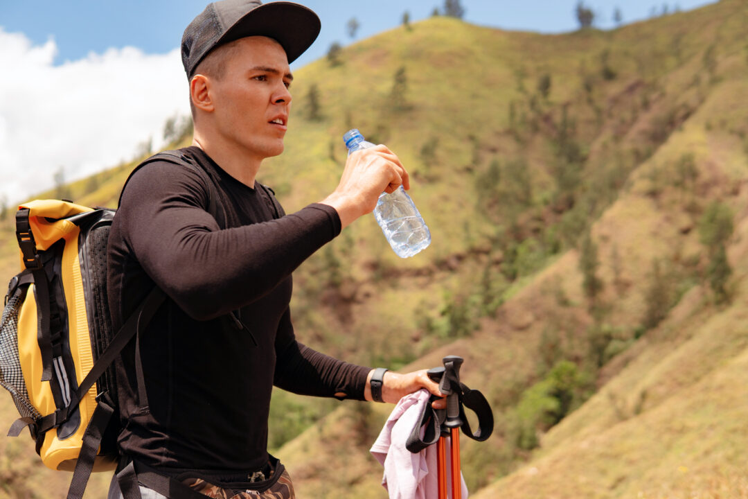Homme qui s'hydrate pendant sa marche en montagne