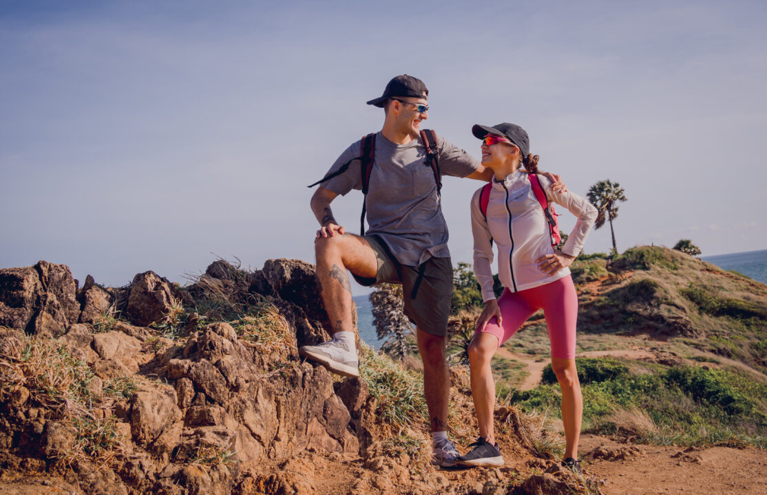 happy young couple climbs to the top in the mountains near the ocean