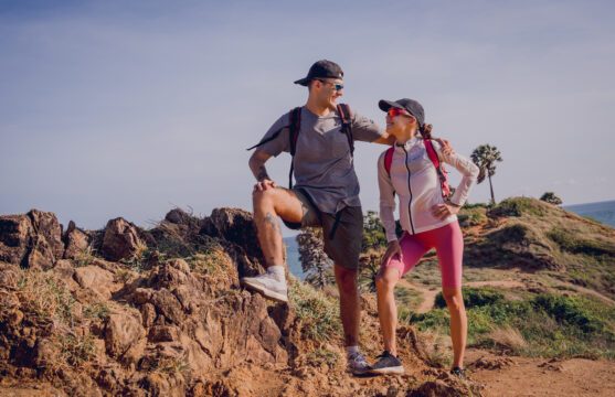 happy young couple climbs to the top in the mountains near the ocean