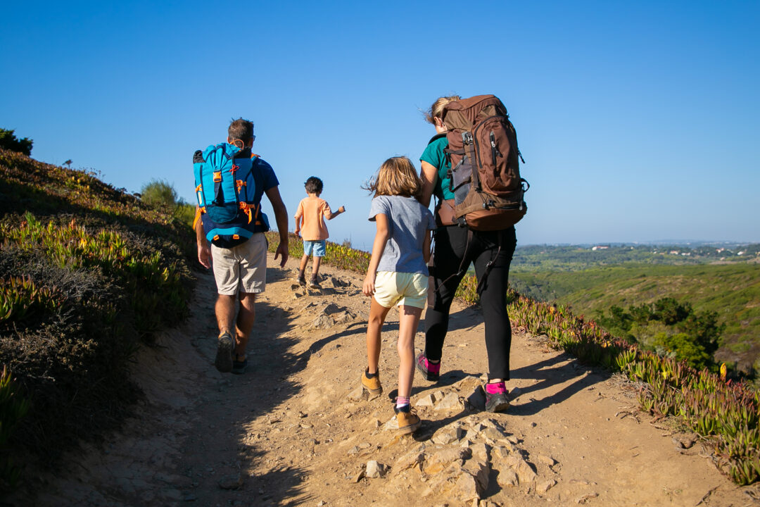family of travelers with backpacks walking on track