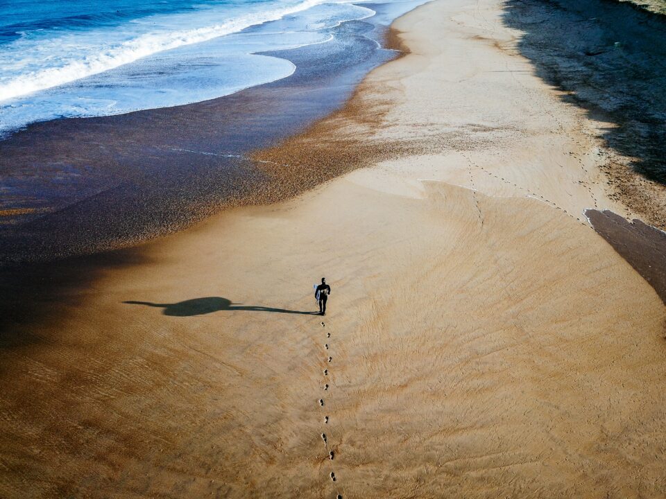 drone shot from surfer walking on the shoreline